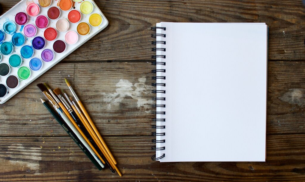 notepad, paintbrushes and paints